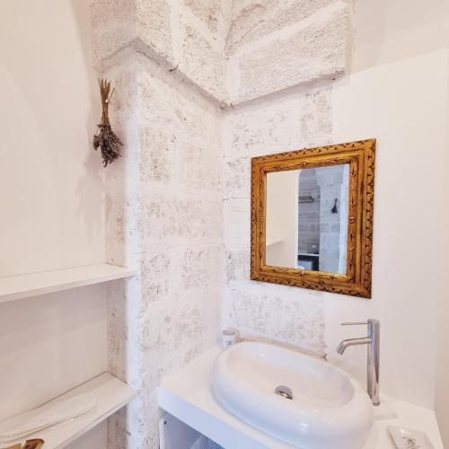 a white bathroom with a sink and a mirror at Corte Mercurio B&B in Ugento