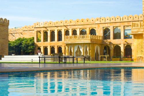 a building with a pool of water in front of it at Fort Rajwada,Jaisalmer in Jaisalmer