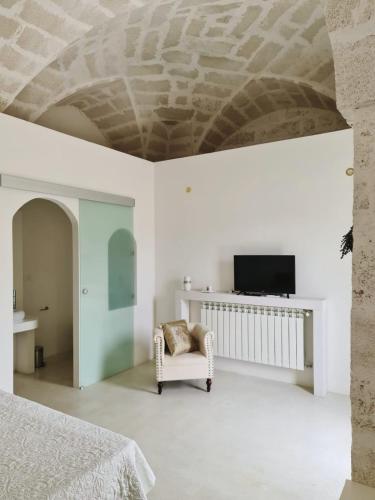 a bedroom with a bed and a tv and a chair at Corte Mercurio B&B in Ugento