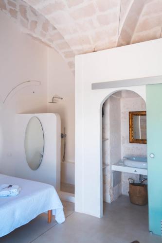 a room with a bed and a bathroom with a sink at Corte Mercurio B&B in Ugento