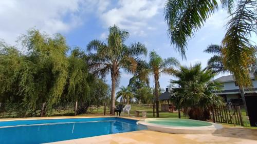 una piscina frente a una casa con palmeras en Cabañas del Paraiso en Colón