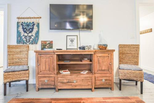 a wooden entertainment center with two chairs in a room at The Captains Quarters - A Relaxing Nautical Abode in Christiansted