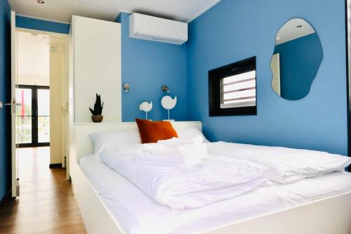 a bedroom with a white bed with a blue wall at Floatinghouses Weserbergland in Höxter