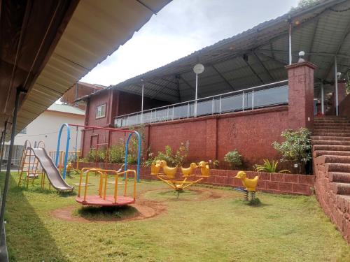 a playground in front of a building with slides at Nisarga Lake Resort Tapola in Satara