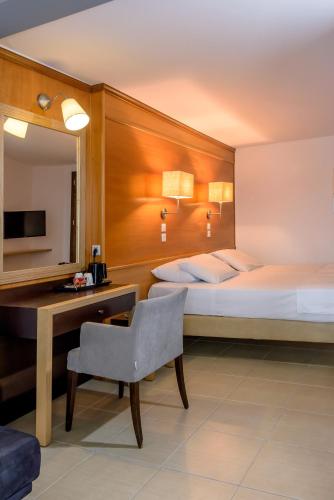 a hotel room with two beds and a desk and a chair at Iraklion Hotel in Heraklio Town