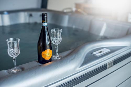 a bottle of wine and two glasses on a sink at RURAL RETREAT WALES Indoor Hot Tub, Log Fire, Starry Skies, Woodland Walks in Llanfyrnach