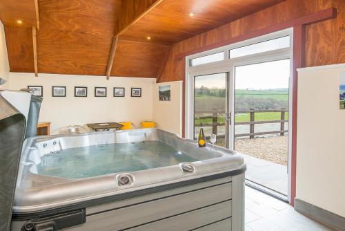 a large tub in a kitchen with a large window at Luxury cottage with private INDOOR hot tub+woodlands in Llanfyrnach
