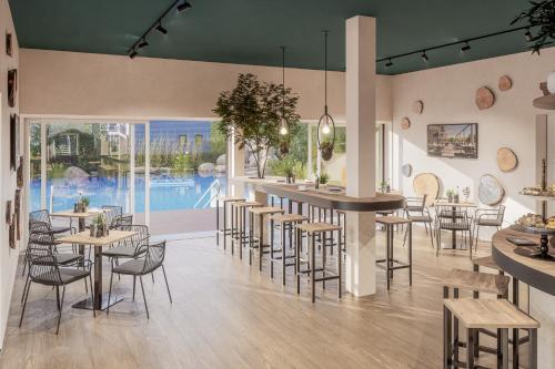 un restaurante con mesas y sillas y una piscina en Prima Resort Boddenblick - Camping & Tiny House-Resort en Groß Kordshagen