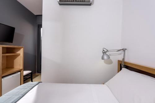 a bedroom with a white bed and a tv at Iraklion Hotel in Heraklio Town