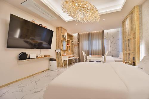 Daegu February Hotel Lions Park في دايغو: غرفة نوم بسرير كبير مع تلفزيون على الحائط