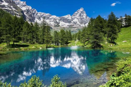 a lake in the mountains with a reflection in the water at FAIRWAY LODGE in Breuil-Cervinia