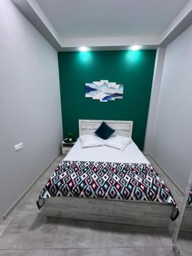 a bedroom with a bed with a green wall at Cosy Apartment with Good Location Self Check In in Yerevan