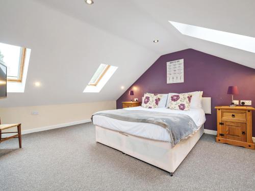 een slaapkamer met een groot bed met een paarse muur bij Carriage House in Penrith