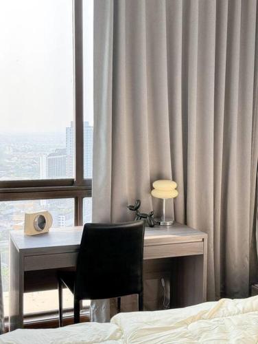 einen Schreibtisch mit Stuhl in einem Zimmer mit Fenster in der Unterkunft HMJ3 Entire Apt on 33rd floor in Khonkaen city center in Khon Kaen