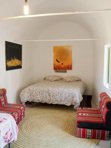- une chambre avec un lit et deux chaises dans l'établissement Maison D'hote Dar Jeddi, à Kreddache