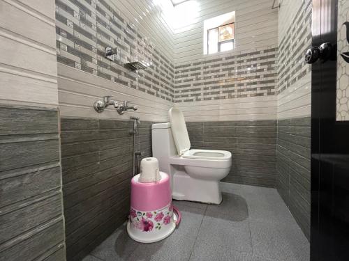 a bathroom with a toilet and a pink stool at RK Residency in Kozhikode