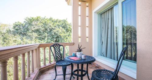a table and chairs on a balcony with a window at Karma Chalets in Gurgaon