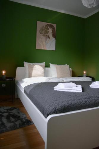 a bedroom with a large bed with a green wall at CROWN apartment 4 in Subotica