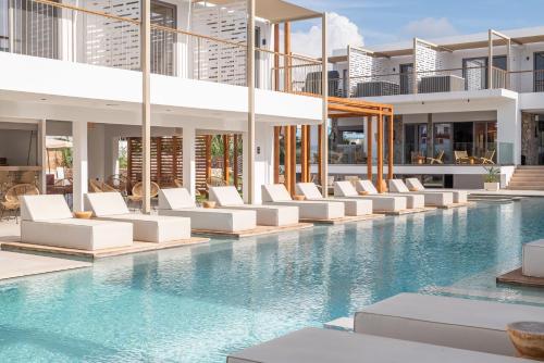 a swimming pool with white lounge chairs in a building at Paralos Kyma Dunes Adults Only in Mastihari