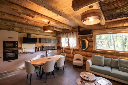 une cuisine et un salon avec une table et des chaises dans l'établissement Gîtes en rondins de Vassivière - Les Fustes de Plazanet, à Faux-la-Montagne