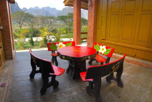 a red table and chairs on a patio with a view at Vang Vieng Romantic Place Resort in Vang Vieng