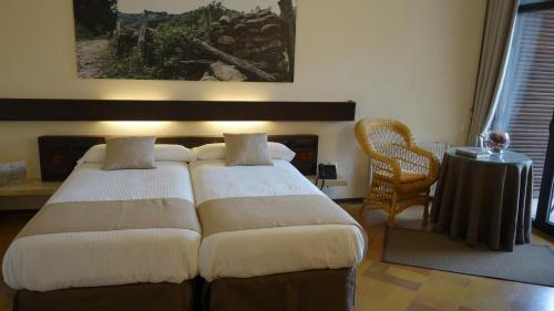 een slaapkamer met 2 bedden en een tafel en een stoel bij Hotel Baztan in Garzáin