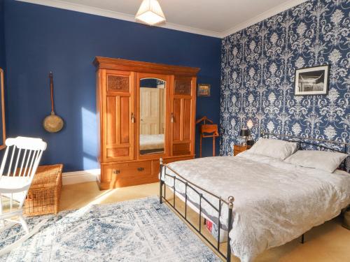 a bedroom with a bed and a blue wall at 3 Forest House in Penrith