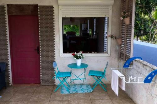 a porch with a table and chairs and a red door at Propriete d'une chambre avec wifi a Petit Bourg a 4 km de la plage in Petit-Bourg