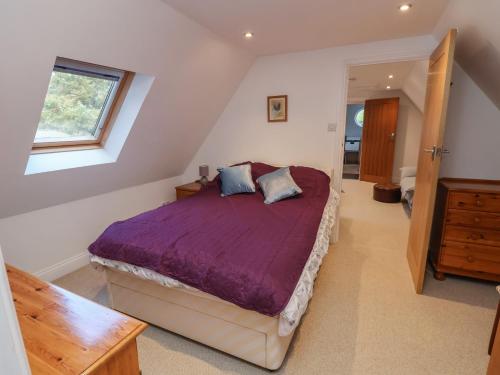 een slaapkamer met een bed met paarse lakens en een raam bij The Chicken Coop in Shrewsbury