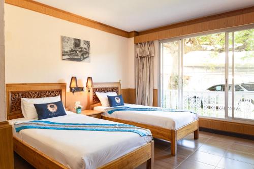 2 bedden in een hotelkamer met een raam bij RoomQuest Golden Triangle Premium Collection in Chiang Saen
