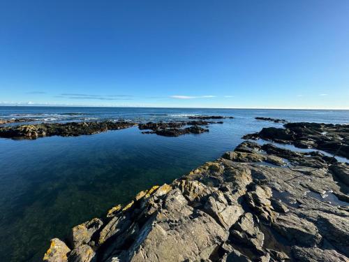 a large body of water with rocks in the water at The Harbour Cottage in Peterhead