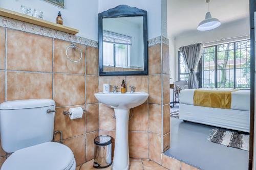 a bathroom with a toilet and a sink and a bed at The Spanish House in Centurion