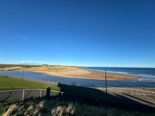 a beach with a fence and the ocean at The Harbour Cottage in Peterhead