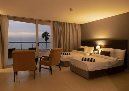 a hotel room with two beds and a table and chairs at O Beach Hotel & Resort in Sowayma