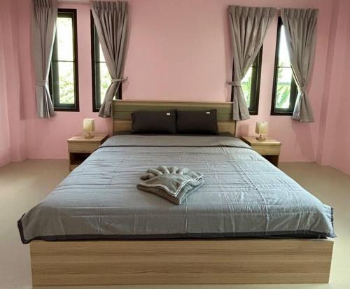 a bedroom with a large bed with pink walls and windows at Villa Patong in Ban Na Nai