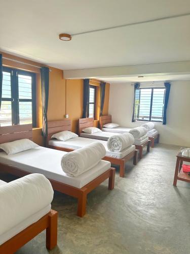 a row of beds in a room with windows at Hill Top Lodge Ghandruk in Astam