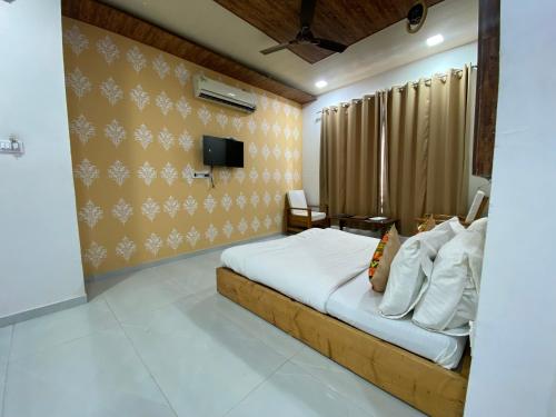マウント・アブにあるRudraksha Innのベッドルーム1室(ベッド1台、壁にテレビ付)