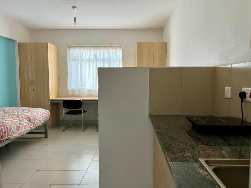 een keuken met een wastafel en een bed in een kamer bij ADANA PODS in Nairobi