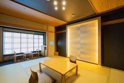 een woonkamer met een tafel en een groot raam bij Ito Kowakien in Ito