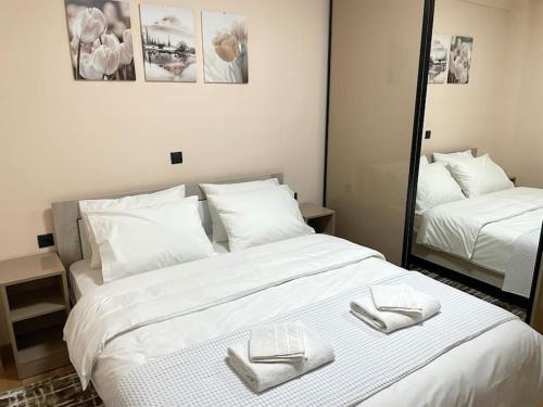 ein großes weißes Bett mit zwei gefalteten Handtüchern darauf in der Unterkunft The MODERN apartment in Thessaloniki