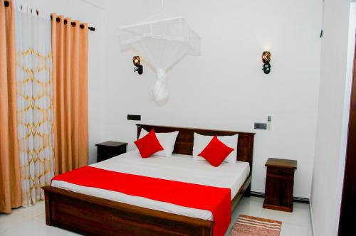 een slaapkamer met een bed met rode en witte kussens bij Sigiri Heaven Villa in Sigiriya