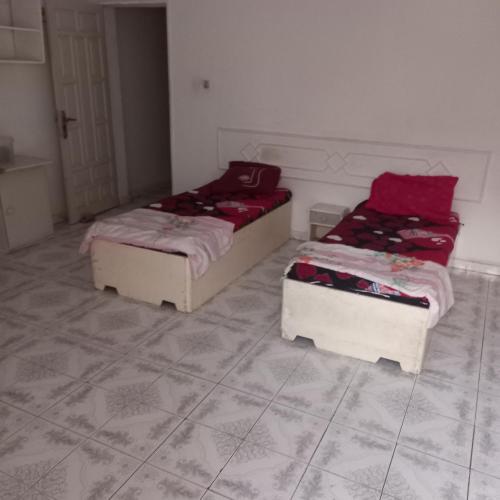 two beds sitting in a room with tile floors at Lakhdar saaoudi in Nouakchott