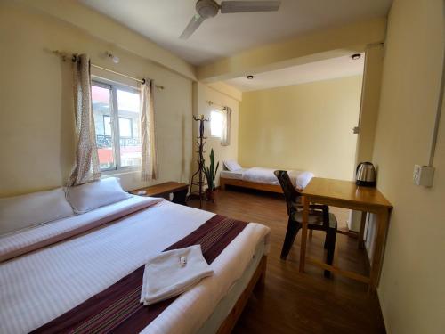 a bedroom with a bed and a desk and a table at Santoshi Guest House and Yoga Center in Pokhara