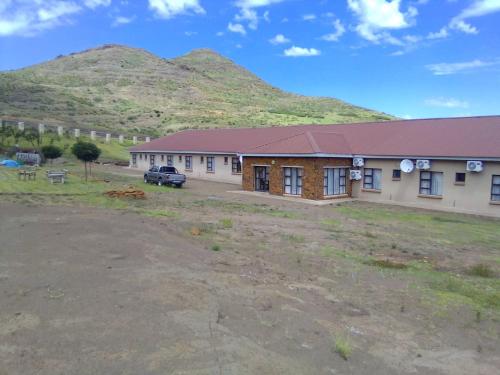 a building with a car parked in front of a mountain at Morning Star Lodge. in Lirahalibonoe