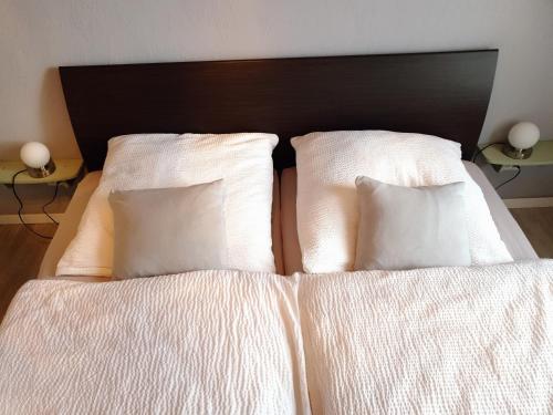 uma cama com lençóis brancos e almofadas em Das Düsselapartment em Haan