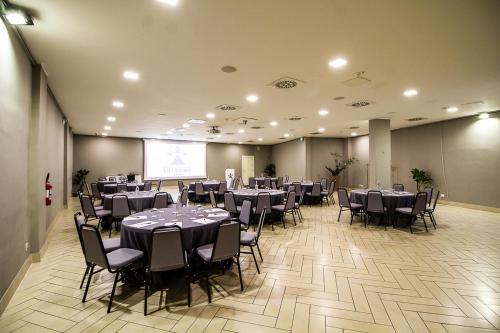 a banquet hall with tables and chairs and a screen at Grand Hotel Villa Itria Congress & Spa in Viagrande