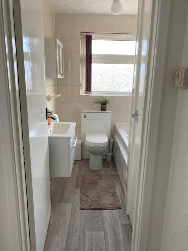 a bathroom with a toilet and a sink and a window at Spacious 2 Bed Village Flat sleeps 4/6 in Nottingham