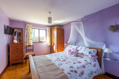 a bedroom with purple walls and a bed and a window at Wheel Cottage, Landrake in Saltash