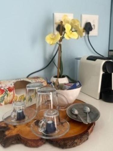 a table with a flower in a vase and glasses at Ecolux in Marracuene