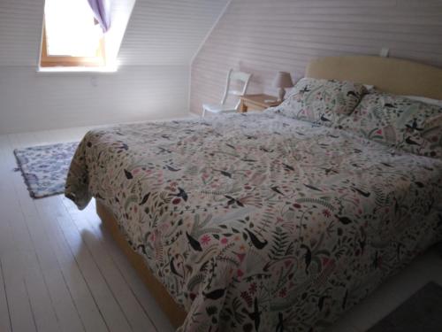 a bedroom with a bed with a comforter on it at Bri29 - Poullaouen - Murmur-y-coed in Poullaouen